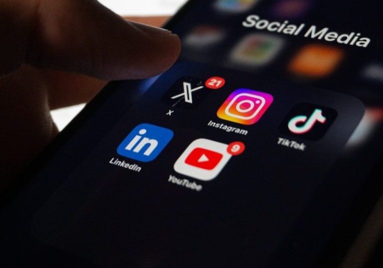 A person holding a smart phone with social media on the screen