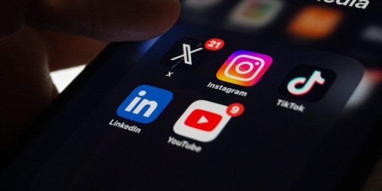 A person holding a smart phone with social media on the screen